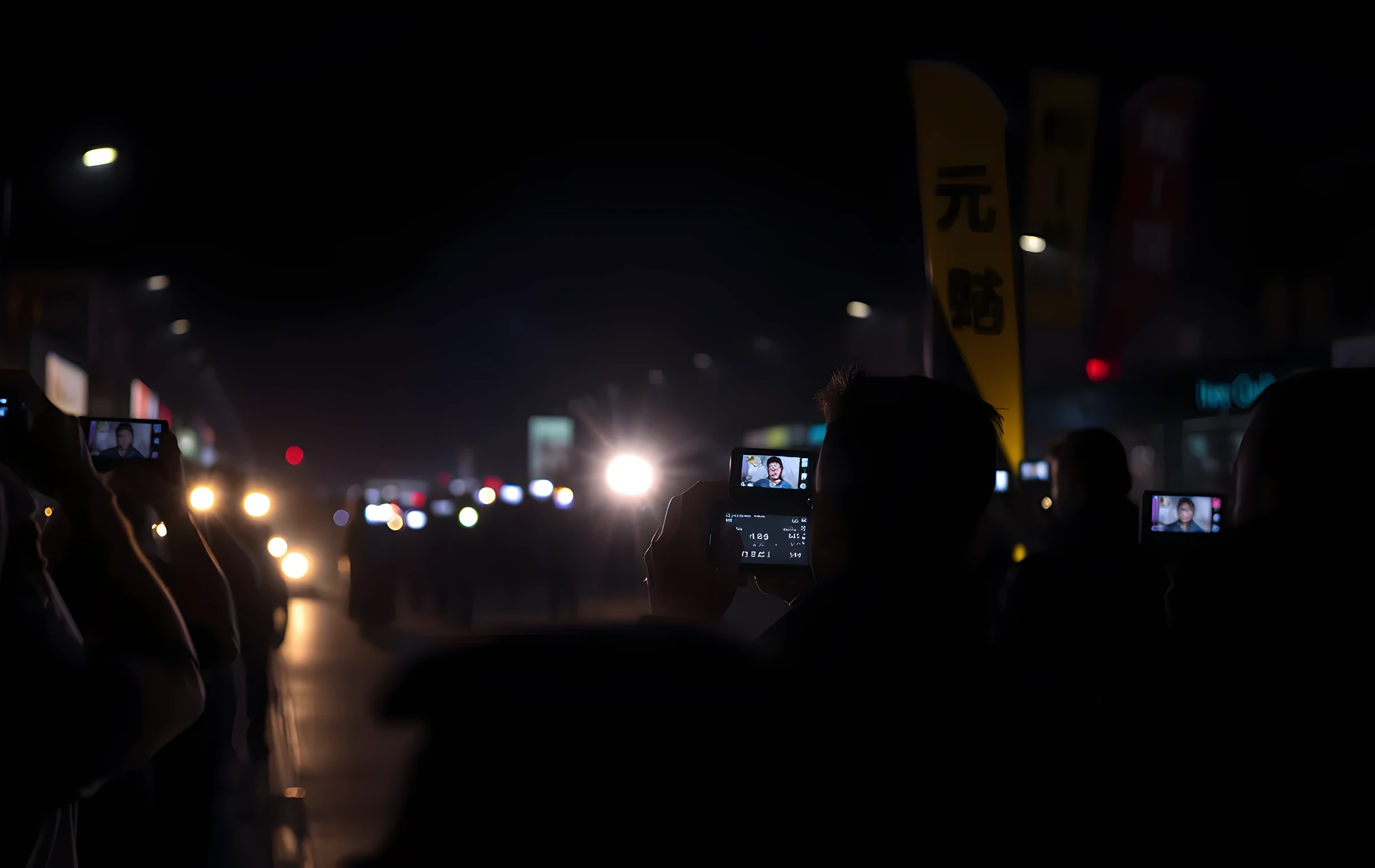 Camera flashes from a crowd of photographers at night, seen from a distance