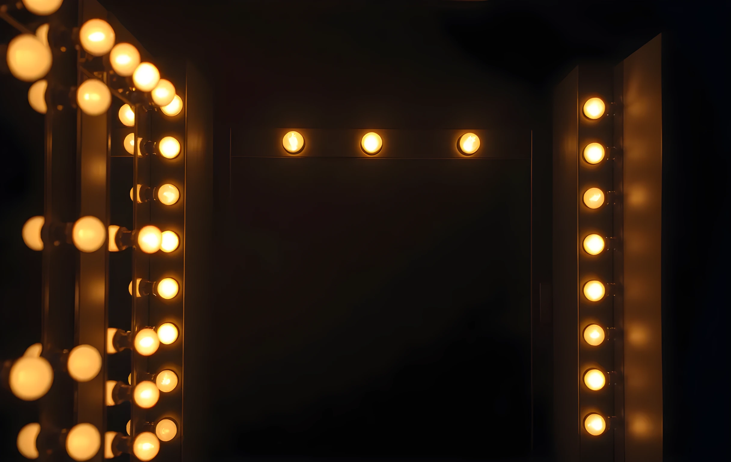 An empty dressing room mirror framed by warm glowing bulbs